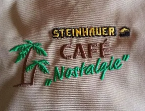 Mehrfarbige Stickerei mit Palmenmotiv auf heller Berufsbekleidung
